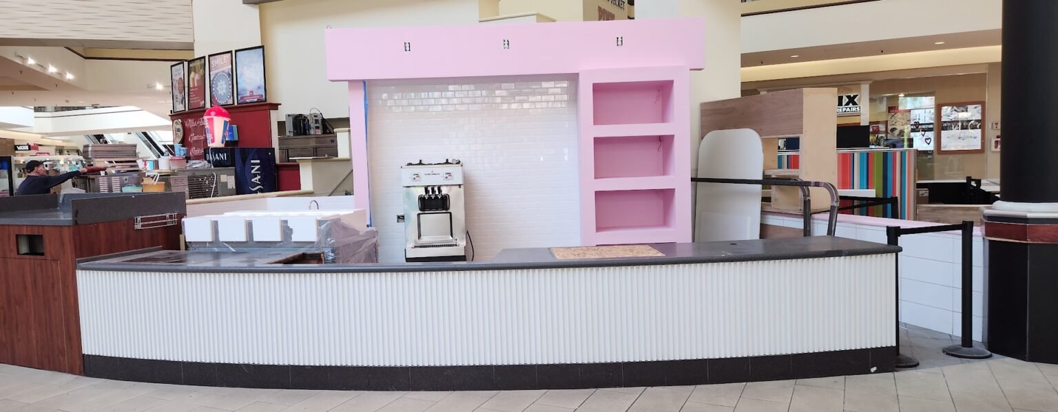 Remodeled food-court kiosk with white tile, pink display shelving and a new service counter