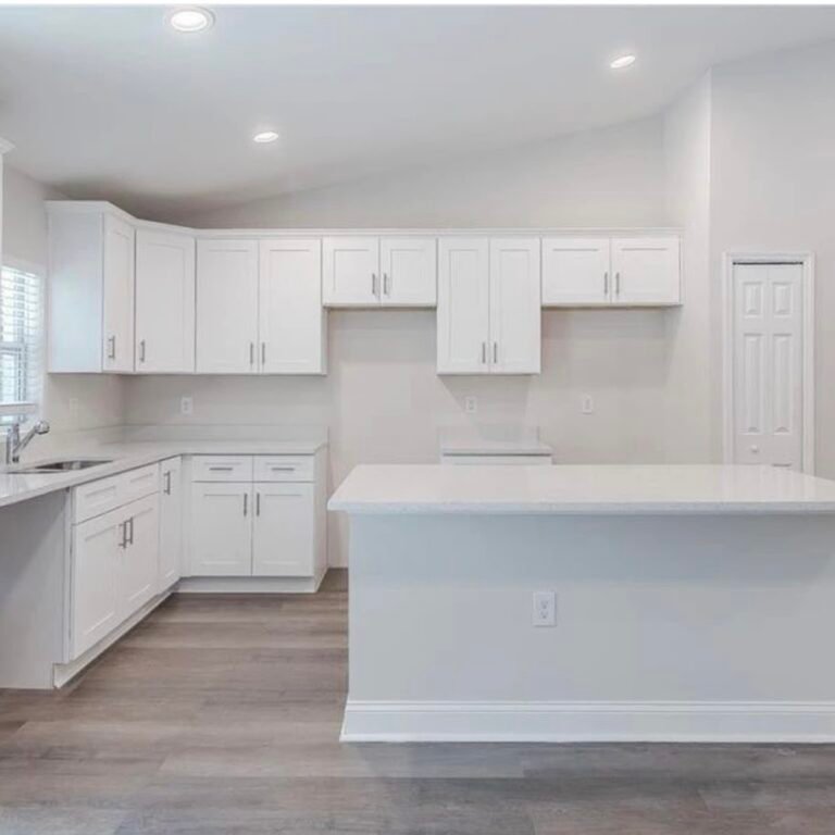 Kitchen with white shaker cabinets, a large island and light countertops