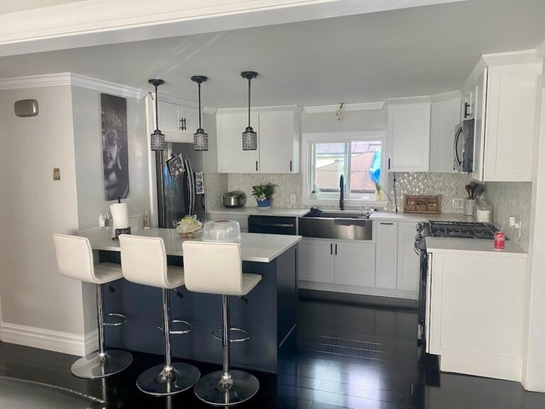 Kitchen with white cabinets and a navy island, completed by CraftWise